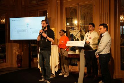 Les participants Octos du hachathon présentent le pitch de leur projet sur une estrade dans un salon du ministère.